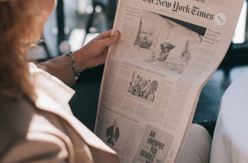 woman holding the new york times newspaper